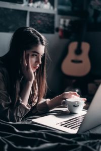 photo of woman lying on bed working from home